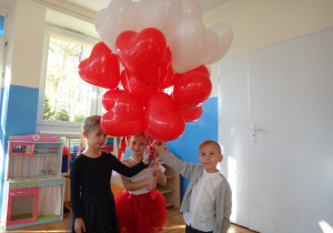 Dzieci stoją z białymi czerwonymi balonami
